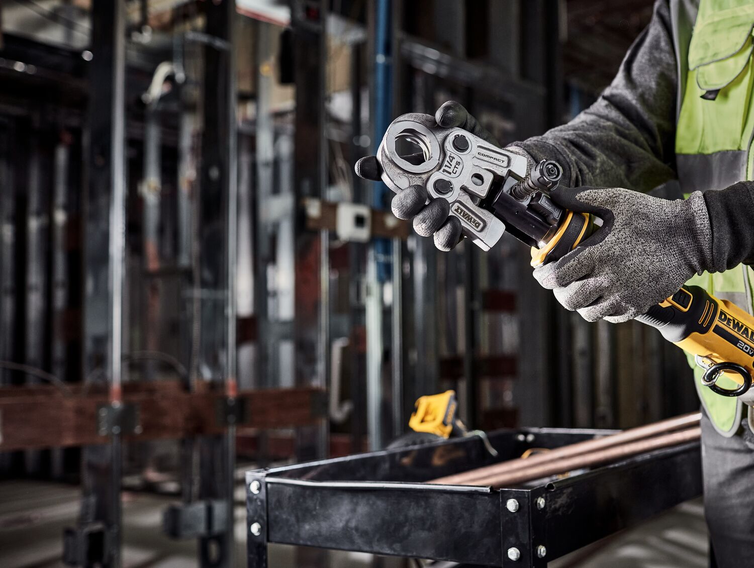 Tradesman is switching the jaw on the DEWALT Compact Press Tool in a mechanical room.