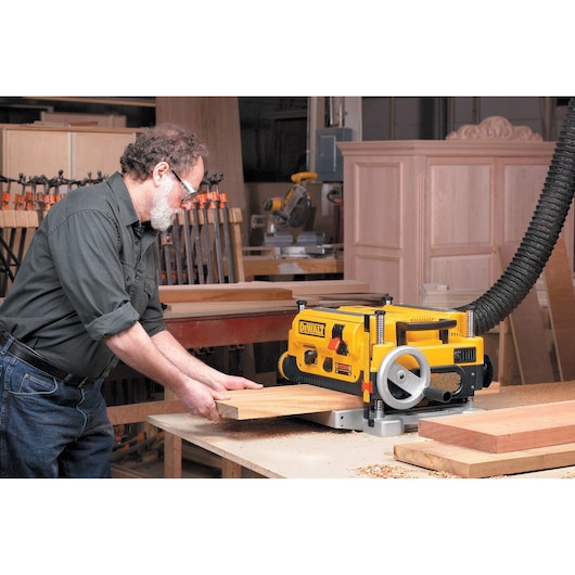 13 inch Three Knife Two Speed Thickness Planer being used by a person on wood.